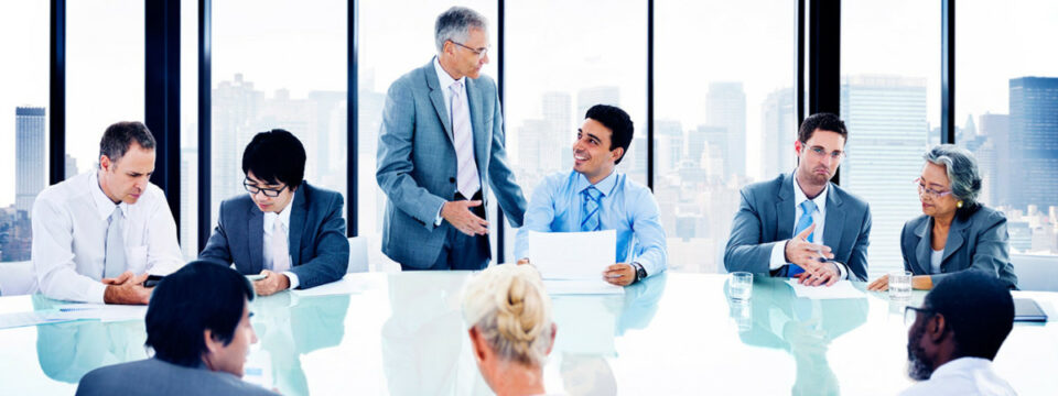 Equipo ejecutivo diverso en reunión de negocios en sala de juntas con vista urbana, liderada por directivo senior.