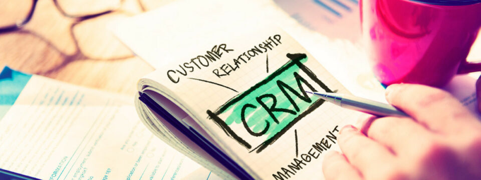 Esquema manuscrito CRM resaltado en verde rodeado de términos Customer Relationship Management en entorno corporativo.