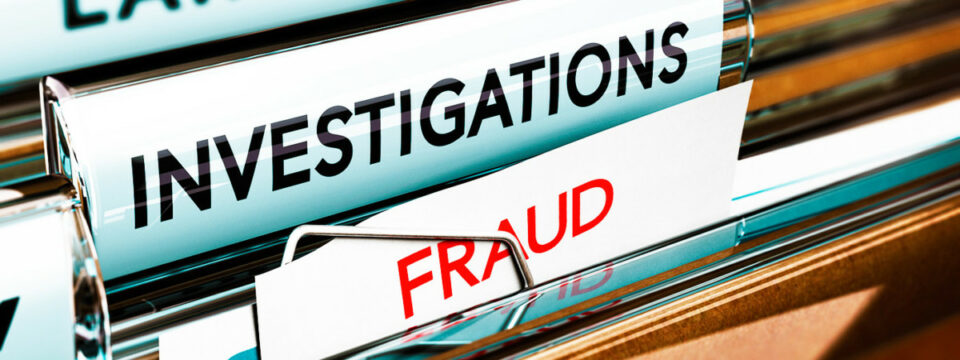 Pestaña de archivo INVESTIGATIONS con nota adjunta FRAUD en rojo resaltado mediante clip metálico en archivador.
