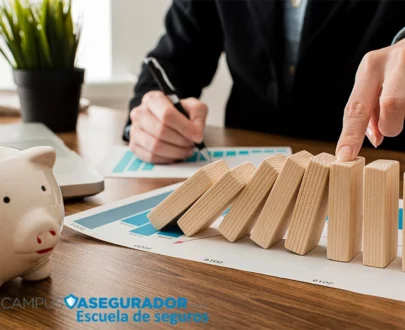 Mano deteniendo caída de domino sobre gráficos financieros junto a hucha y logotipo de Campus Asegurador.