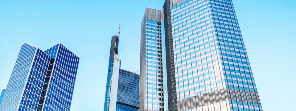 Rascacielos modernos del distrito financiero de Frankfurt destacando la Commerzbank Tower bajo cielo azul despejado.