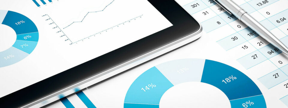 Tablet y documentos impresos con gráficos circulares, de líneas y tablas numéricas junto a un bolígrafo profesional.