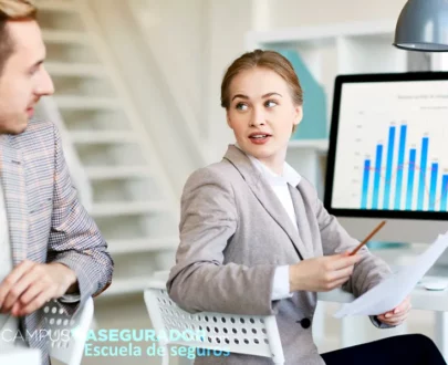 Profesionales analizan gráficos financieros en Campus Asegurador, Escuela de seguros, durante formación técnica avanzada.