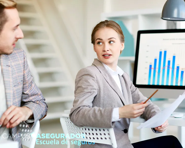 Profesionales analizan gráficos financieros en Campus Asegurador, Escuela de seguros, durante formación técnica avanzada.