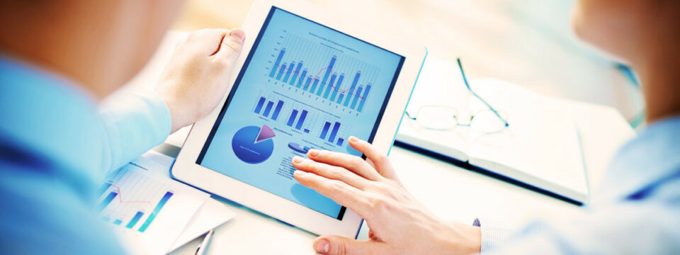 Analistas examinando gráficos financieros y métricas de rendimiento en tablet durante sesión de business intelligence.