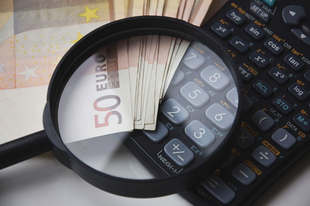Auditoría Financiera y Contabilidad con Divisa Euro Lupa sobre billetes de 50 euros y calculadora científica en contexto de auditoría, contabilidad y análisis financiero.