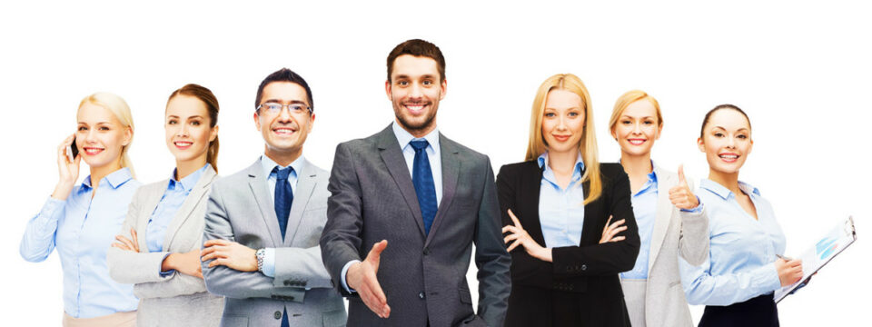 Equipo corporativo en trajes, hombre central ofrece apretón de manos como gesto de bienvenida y alianza profesional.