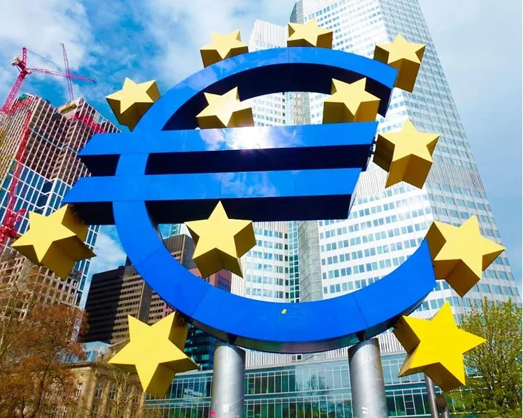 Escultura símbolo euro azul con estrellas amarillas frente a rascacielos financieros en Frankfurt am Main, Alemania.