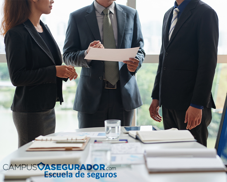 Profesionales en reunión técnica analizando documentos para Campus Asegurador, Escuela de Seguros.