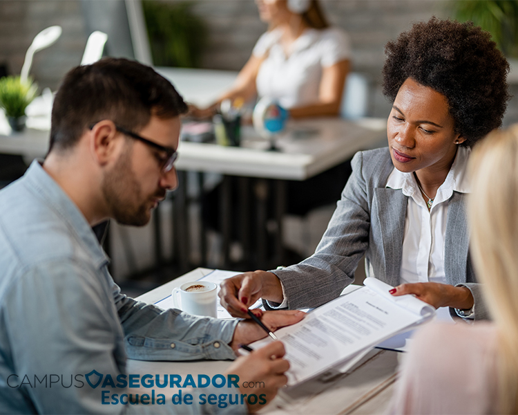 Profesional de seguros revisando contrato con cliente en oficina de Campus Asegurador Escuela de Seguros.