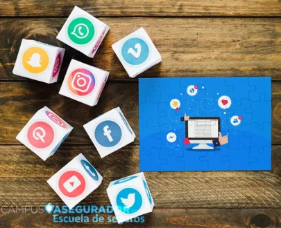 Iconos de redes sociales en cubos y puzzle con monitor sobre madera para estrategias de marketing en seguros.