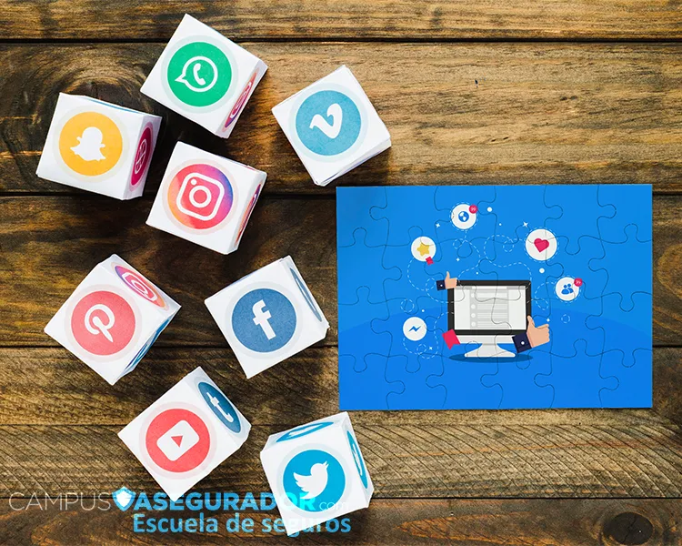 Iconos de redes sociales en cubos y puzzle con monitor sobre madera para estrategias de marketing en seguros.