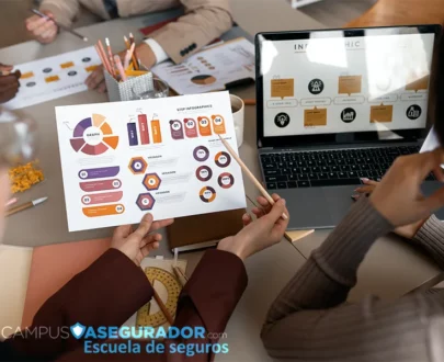 Profesionales analizando infografías y laptop en Campus Asegurador, escuela especializada en el sector de seguros.