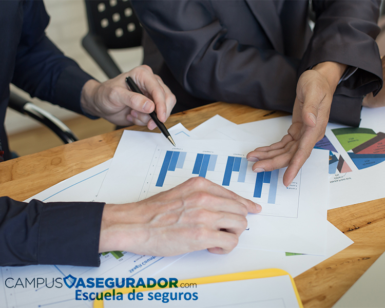 Profesionales analizando informes y gráficos estadísticos durante una clase en la Escuela de Seguros Campus Asegurador.
