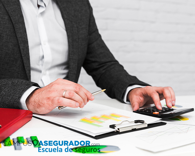 Profesional analizando gráficos con calculadora para formación técnica en Campus Asegurador, escuela de seguros.