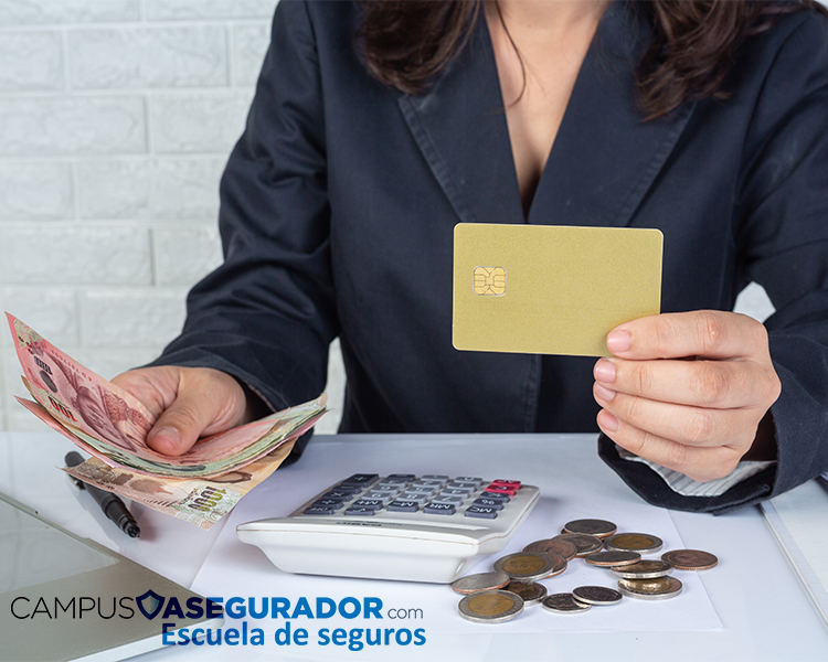 Persona con traje sostiene tarjeta dorada y billetes sobre mesa con calculadora, monedas y logo de Campus Asegurador.