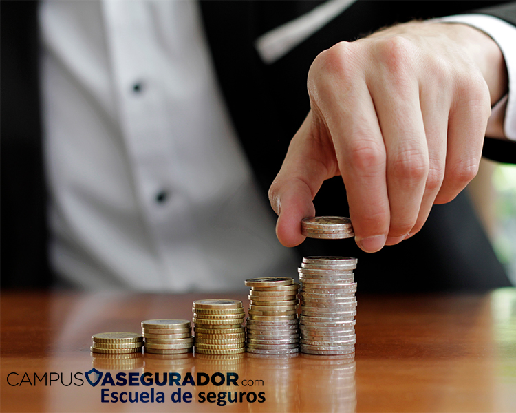 Mano de profesional apilando monedas en columnas crecientes, representando ahorro y capitalización en sector seguros.