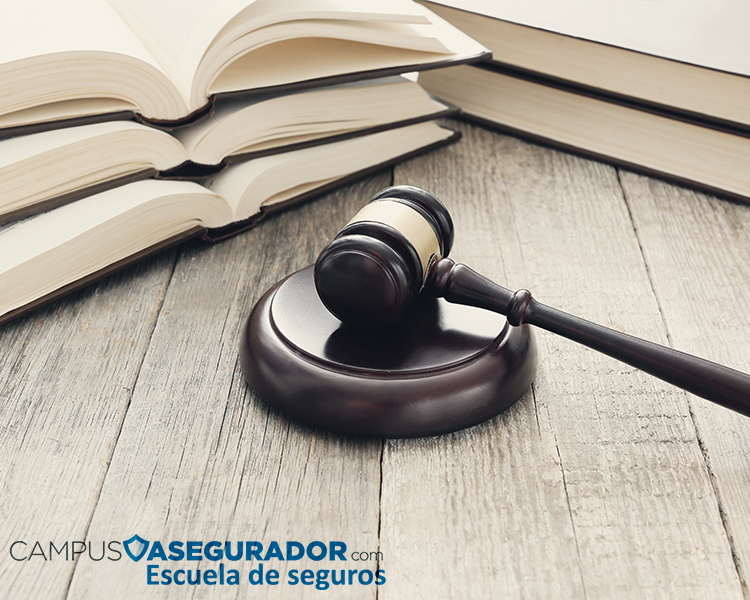 Mazo madera juez sobre bloque sonido y libros legales abiertos en mesa rústica con logo Campus Asegurador.