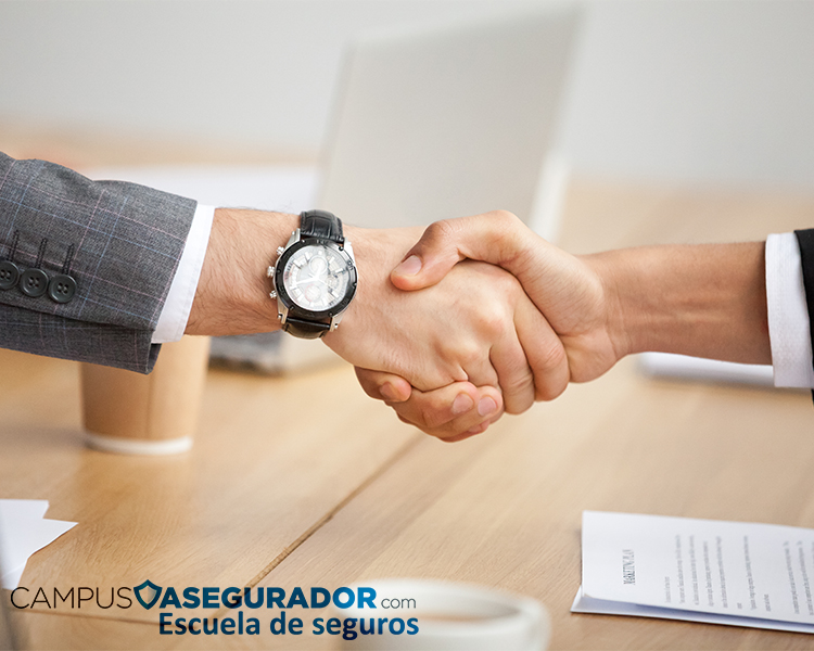 Apretón de manos entre profesionales sobre escritorio con logo de Campus Asegurador y documento de plan de marketing.