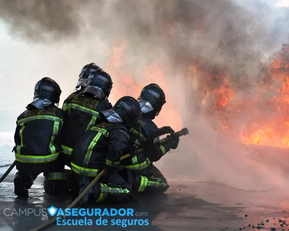 Bomberos de Barcelona con equipo de protección operando manguera de alta presión frente a llamas y humo denso.
