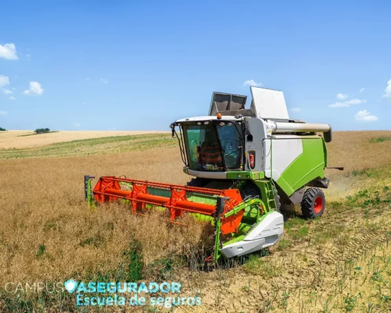 Cosechadora agrícola operando en campo de cultivo seco bajo cielo azul para gestión de seguros de maquinaria pesada.