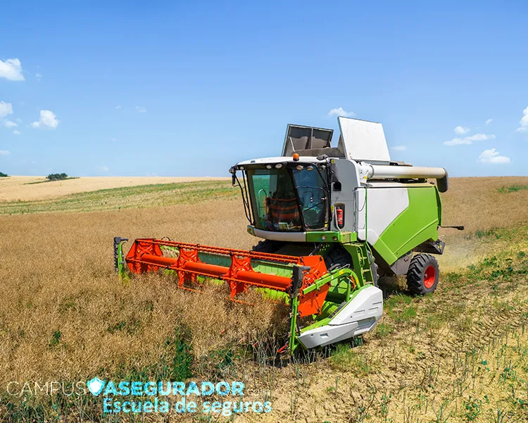 Cosechadora agrícola operando en campo de cultivo seco bajo cielo azul para gestión de seguros de maquinaria pesada.