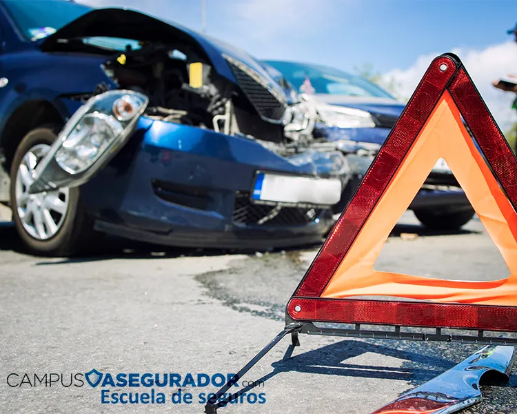 Vehículo azul con daños frontales severos y triángulo de preseñalización de peligro naranja tras accidente vial.