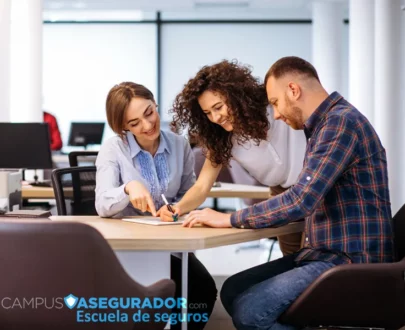 Tres personas colaborando y revisando documentos en la Escuela de Seguros Campus Asegurador.