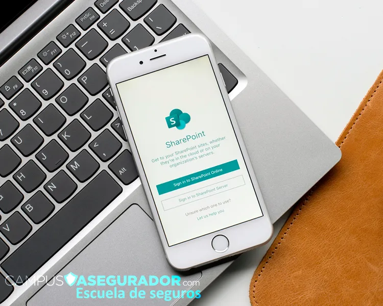 iPhone con app de Microsoft SharePoint abierta sobre teclado de laptop, mostrando opciones de autenticación corporativa.
