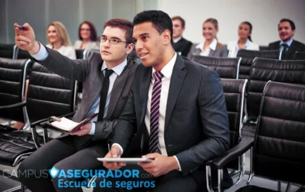 Alumnos en formación técnica de seguros de Campus Asegurador con dispositivos digitales y material de estudio en aula.