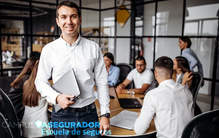 Profesional de Campus Asegurador con portátil en oficina moderna durante curso de formación técnica en seguros.