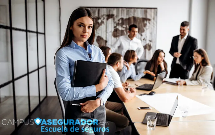 Mujer profesional con carpeta liderando equipo en oficina de Campus Asegurador Escuela de Seguros.