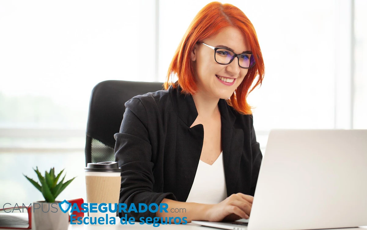 Profesional con gafas y portátil en oficina, marca Campus Asegurador Escuela de seguros.