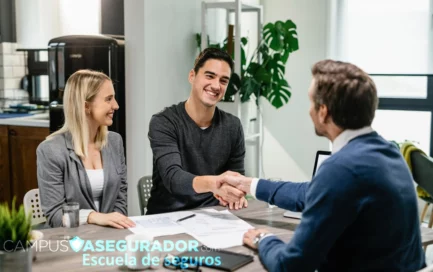 Pareja estrecha mano con asesor frente a documentación contractual en entorno profesional de Campus Asegurador.