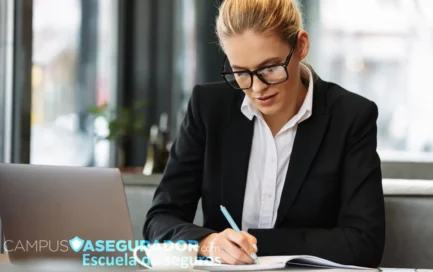 Mujer con gafas y blazer escribiendo en libreta junto a logo de Campus Asegurador y ordenador portátil.