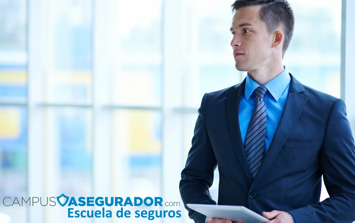 Profesional del sector seguros con tablet frente al logotipo de Campus Asegurador Escuela de seguros en oficina corporativa.