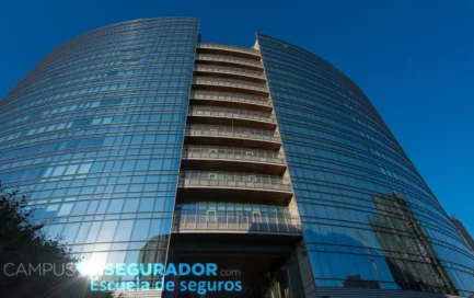 Edificio corporativo de cristal curvo con logotipo de Campus Segurador bajo un cielo azul despejado.