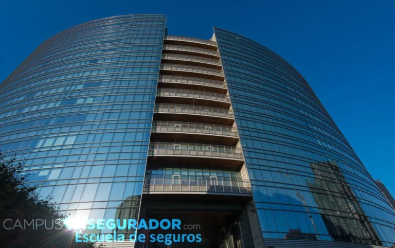Edificio corporativo de cristal curvo con logotipo de Campus Segurador bajo un cielo azul despejado.