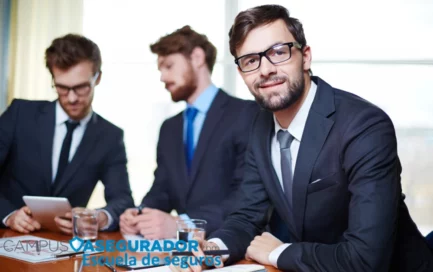 Tres ejecutivos en reunión de Campus Asegurador analizan datos en tablet y bloc de notas en oficina corporativa.