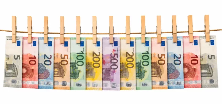 Metáfora de Blanqueo de Capitales y Divisa Euro Billetes de euro de varias denominaciones sujetos con pinzas de madera en un tendedero sobre fondo blanco minimalista.
