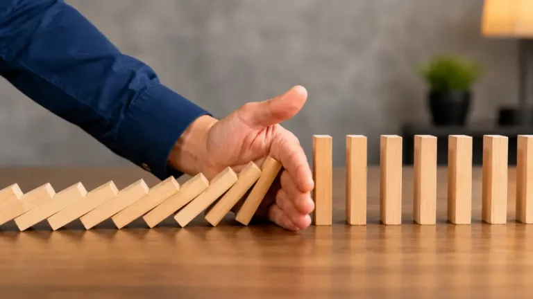 Estrategias de Gestión de Riesgos y Prevención de Crisis Mano profesional deteniendo efecto dominó para representar gestión de riesgos y prevención de crisis empresarial.